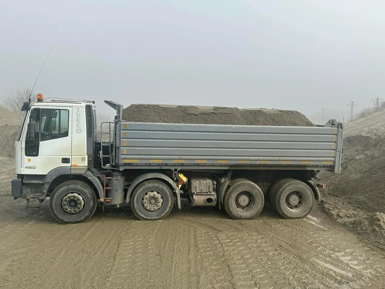 Basculantă 8x4 văzută din lateral, încărcată cu agregate