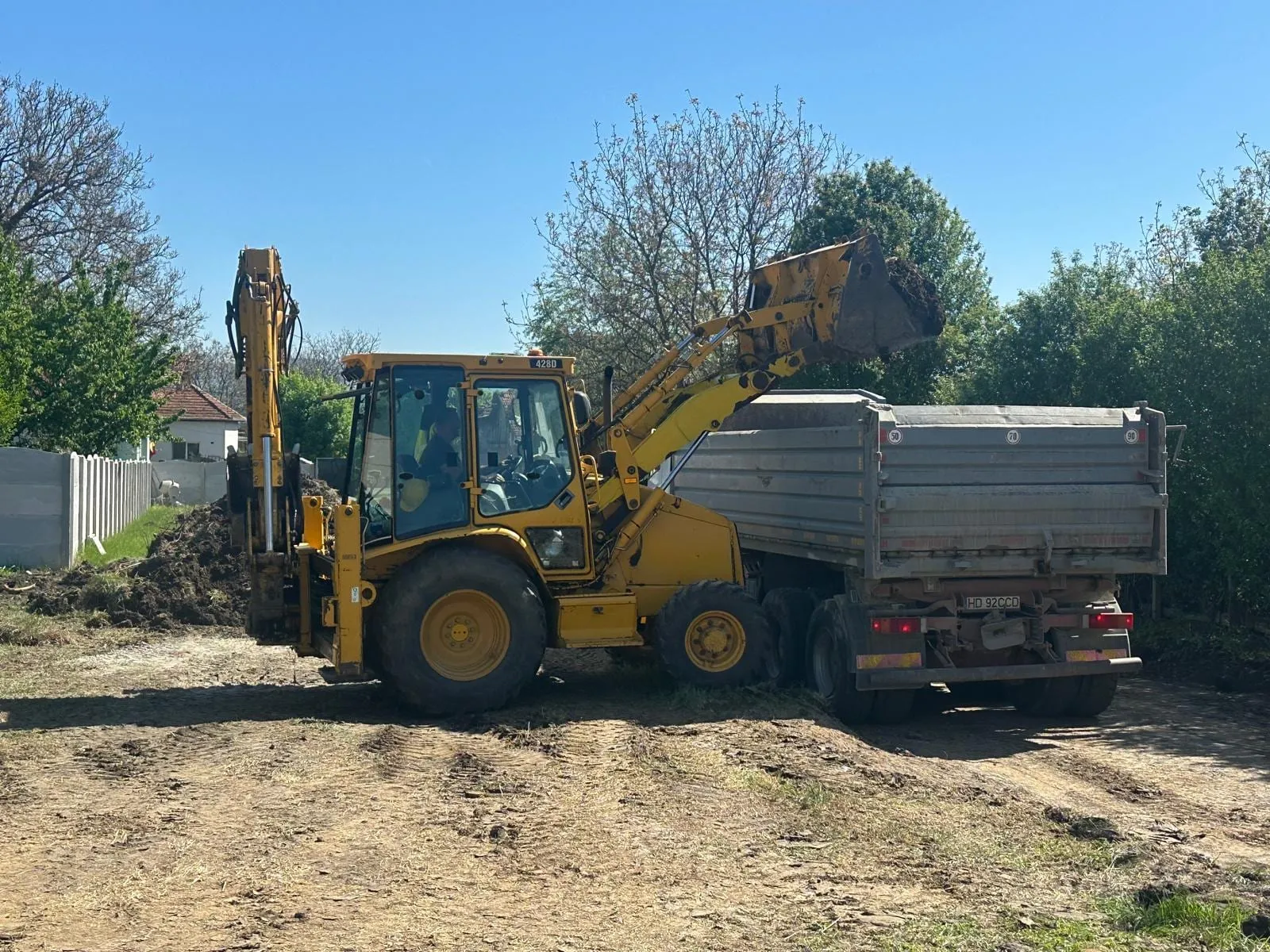 Buldoexcavator care încarcă agregate într-o basculantă